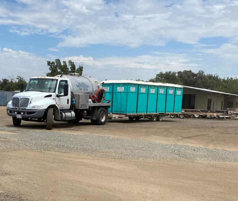 Dedicated service truck driver cleaning a construction-site portable toilet for a Porta potty rental in Hanford, CA account.