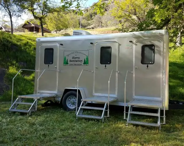 restroom.webp	Three-door silver luxury restroom trailer by Sierra Sanitation parked on a green hillside with stairs and handrails
