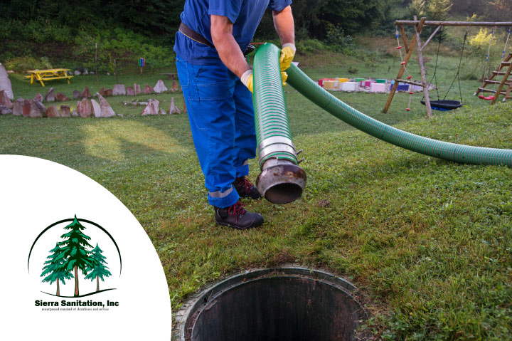 Sierra Sanitation service technician in Visalia, CA, carefully maneuvering a professional suction hose to pump a residential septic tank located under a manicured lawn, ensuring clean and efficient waste removal