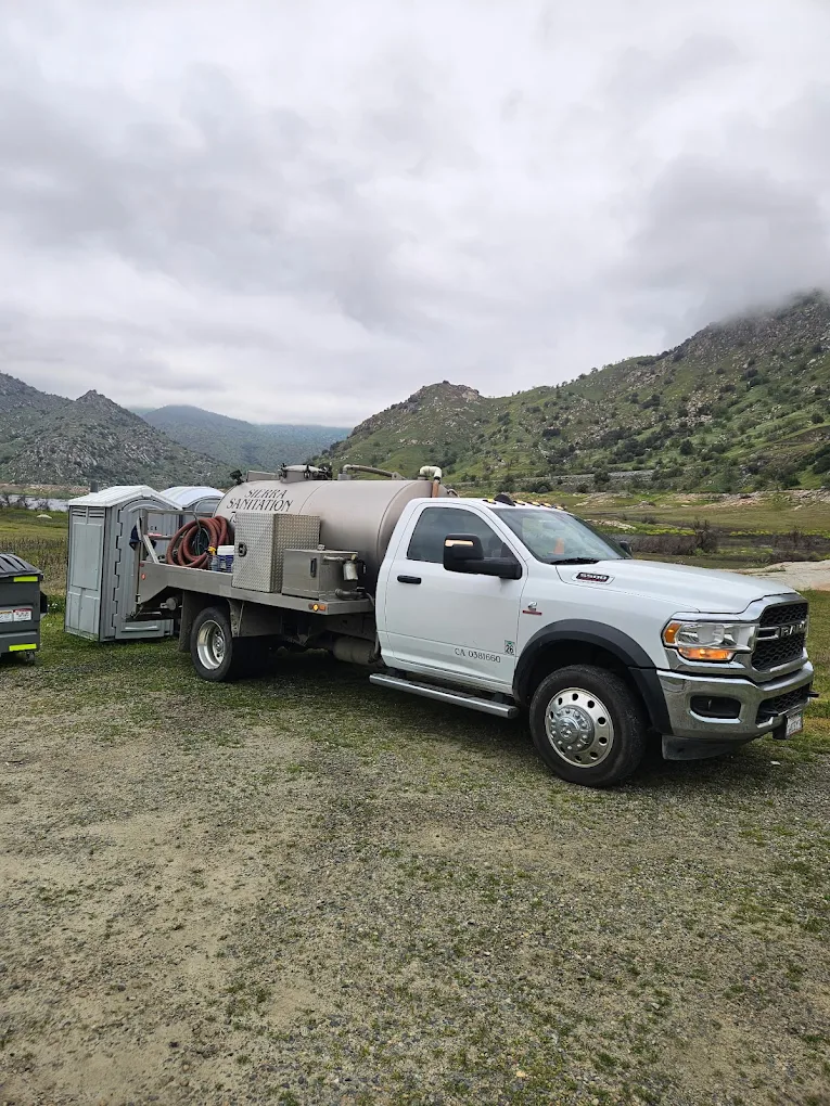 Sierra Sanitation septic system tank service truck parked at a remote site near the Sierra Nevada foothills, providing holding tank pumping for portable units and trailers.
