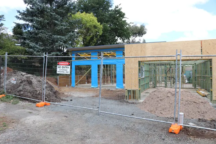 Temporary wire construction fence panel on orange stands with a red Danger No Entry sign securing a residential framing project.